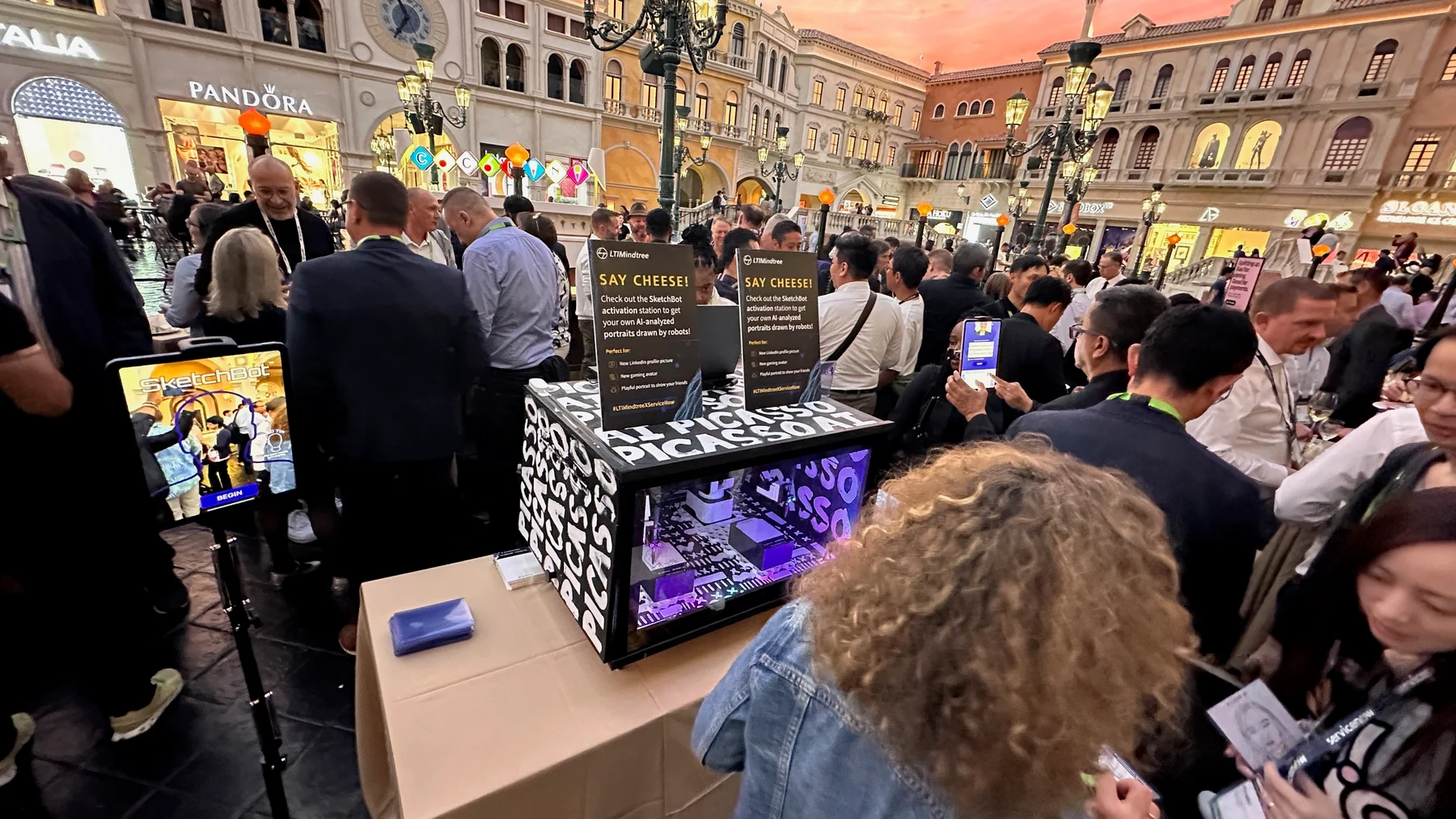 Wide reception view showing crowded SketchBot activation table