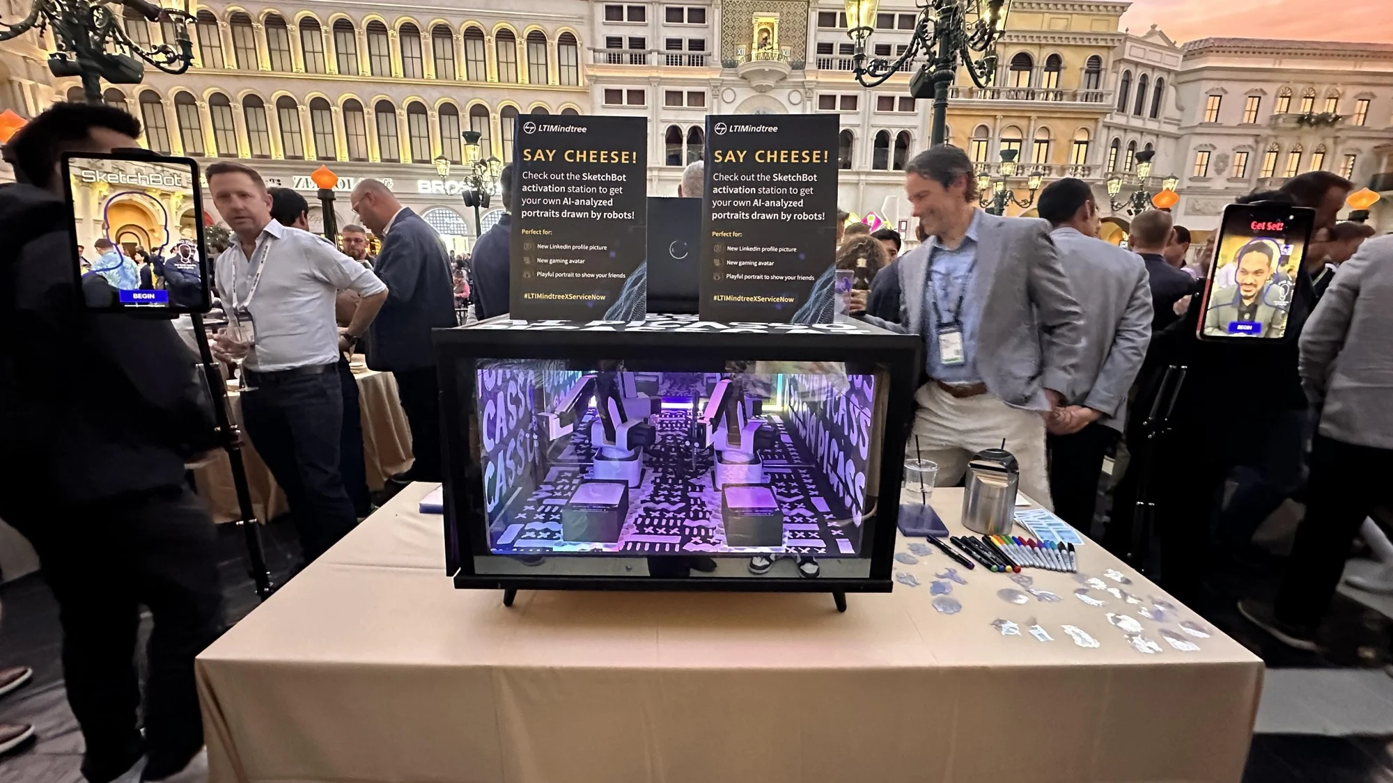 Two capture stations beside the illuminated SketchBot drawing enclosure at the reception