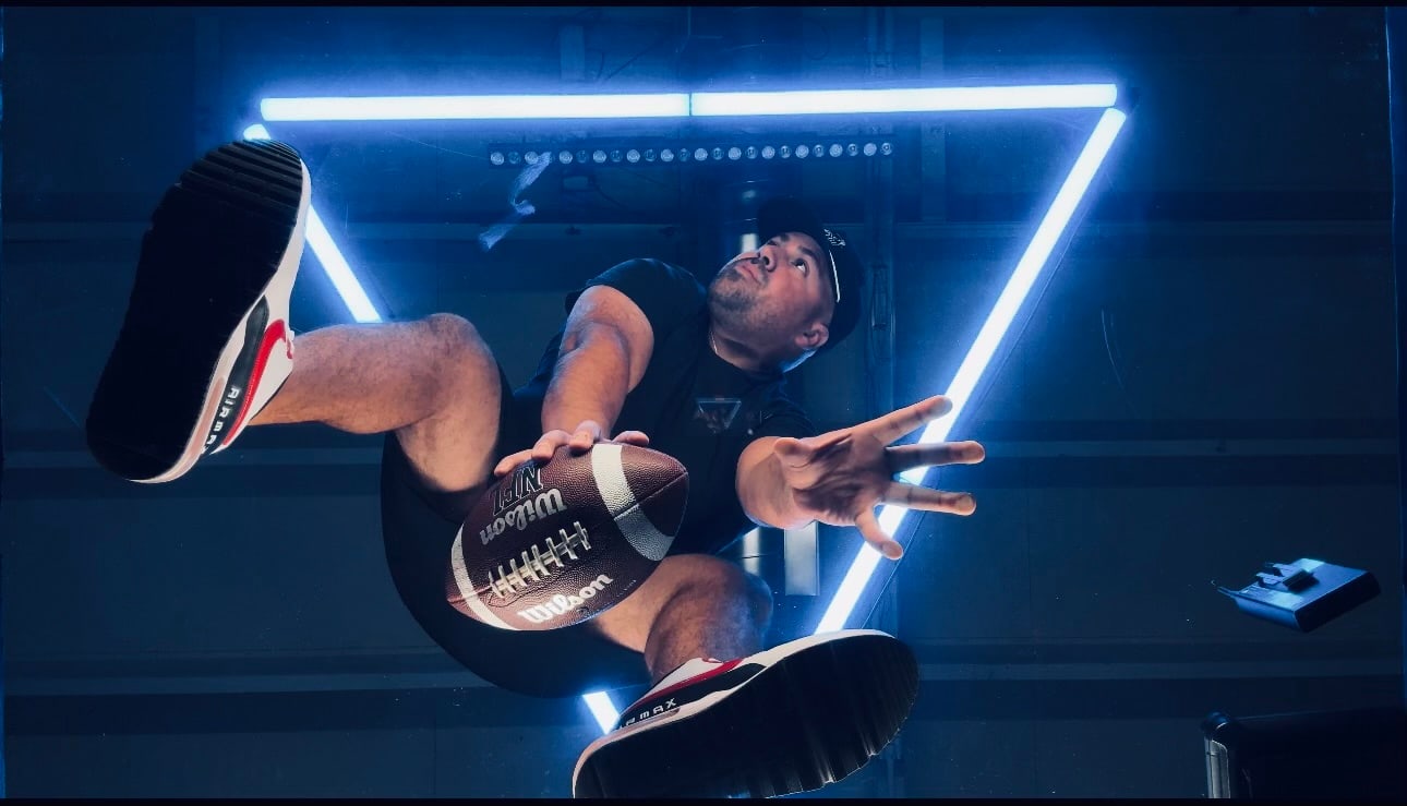 Low-angle Hovr portrait of a participant with a football beneath an illuminated triangle
