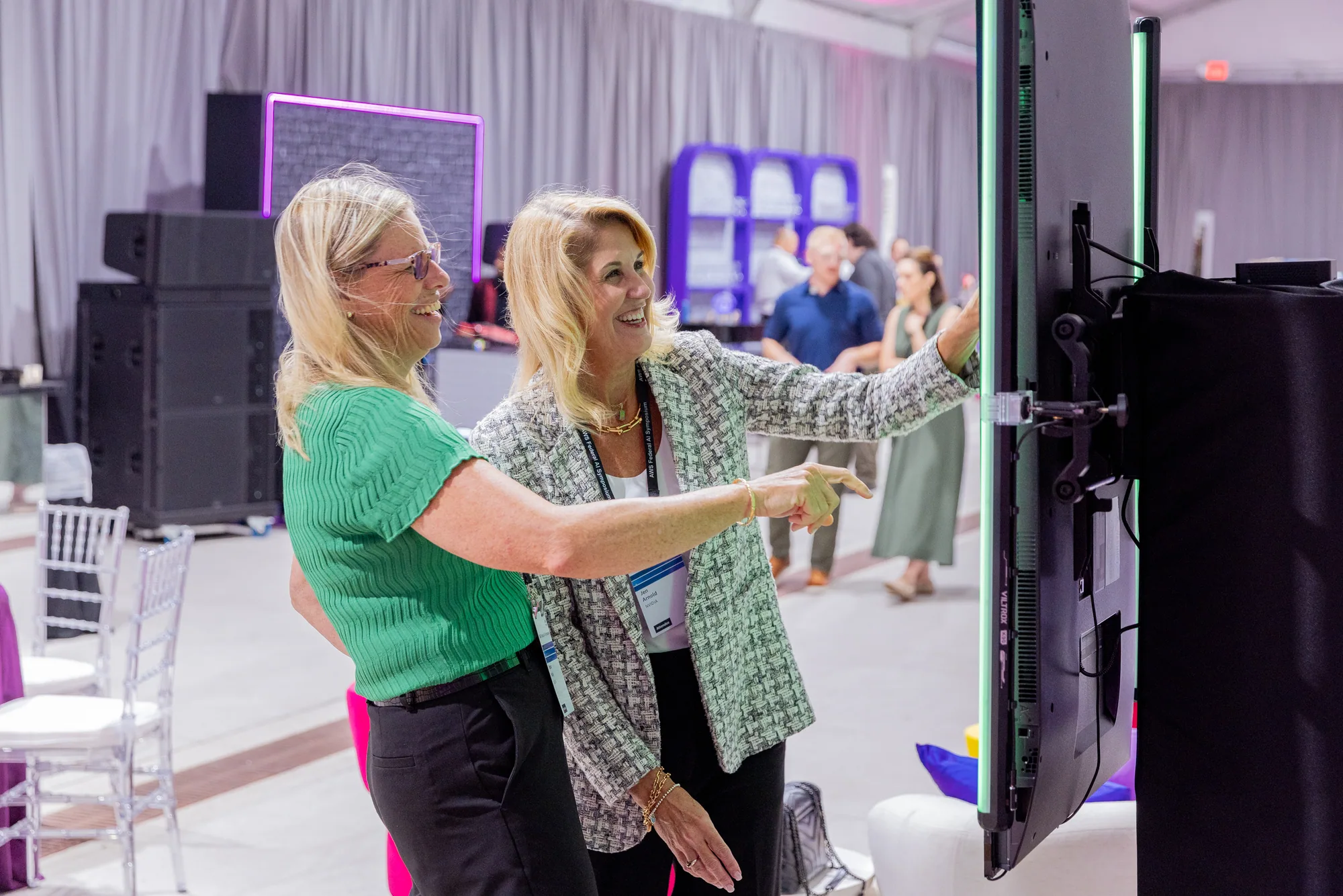 Two attendees stand beside an NVIDIA Match Game touchscreen.