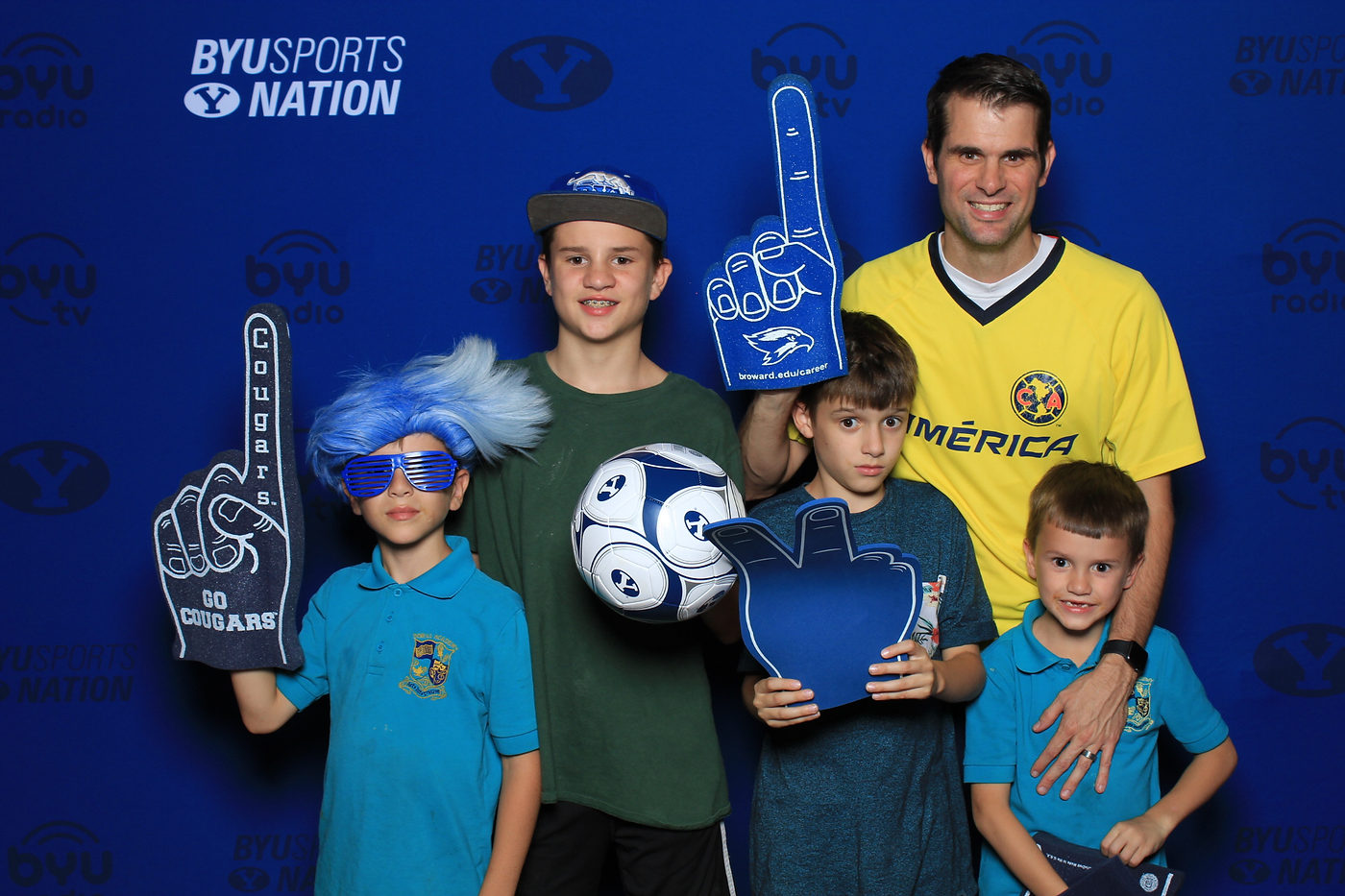Family posing with team props at the BYU Sports Nation photo setting