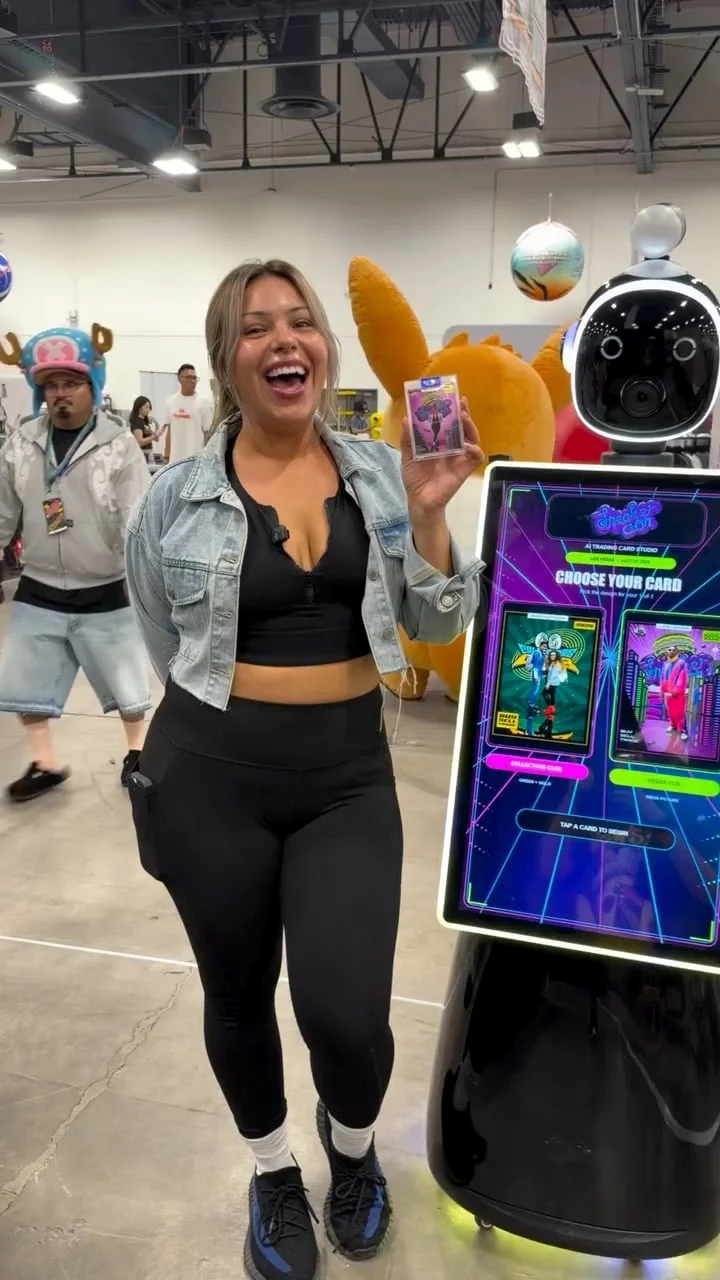 SneakerCon guest with a finished trading card beside SnapBot Rosie